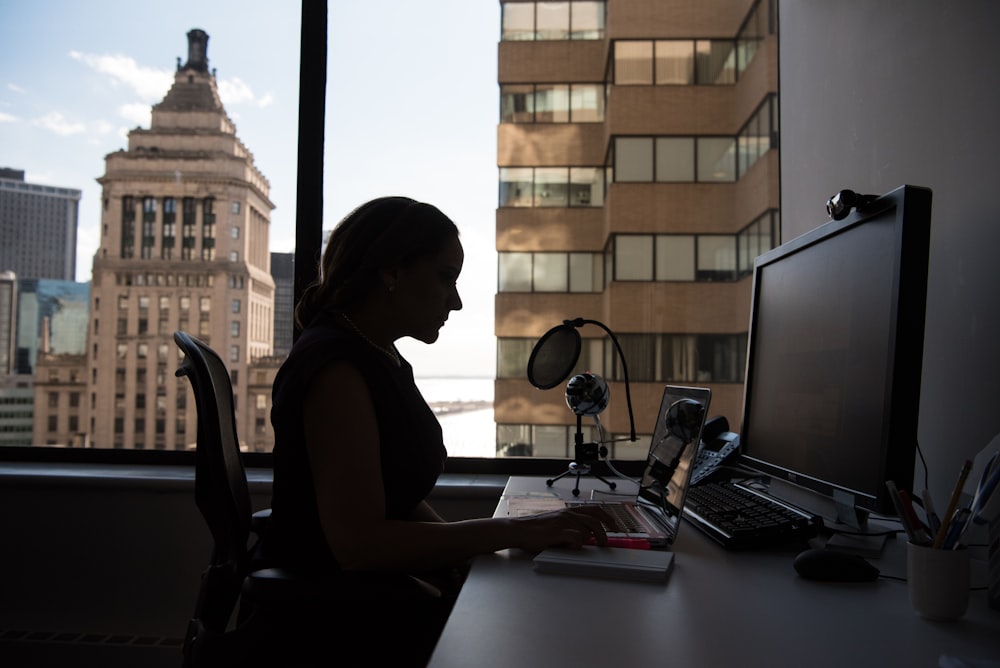 woman sitting in front of desk with computer monitor and keyboard on top